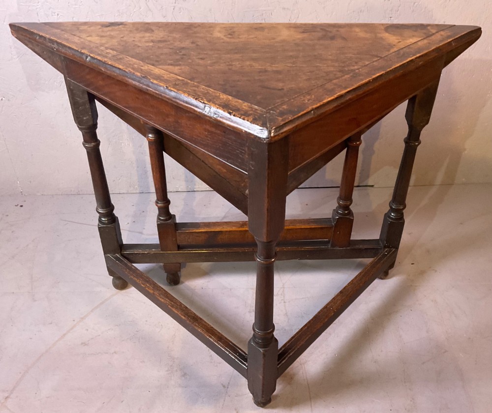 A 17th-century oak credence table featuring a triangular folding top resting on a framework with turned legs and low stretchers. View VII