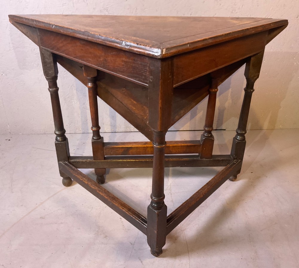 A 17th-century oak credence table featuring a triangular folding top resting on a framework with turned legs and low stretchers. View VIII