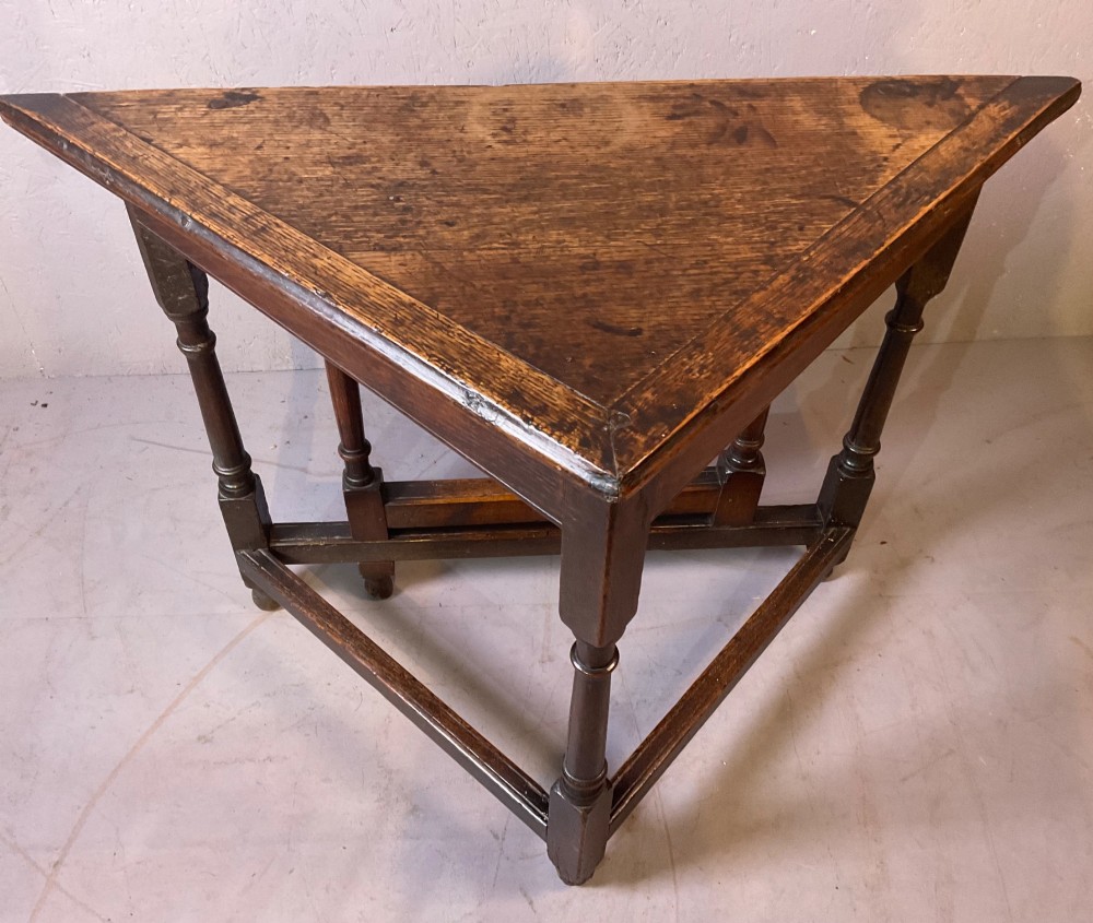 A 17th-century oak credence table featuring a triangular folding top resting on a framework with turned legs and low stretchers. View IX
