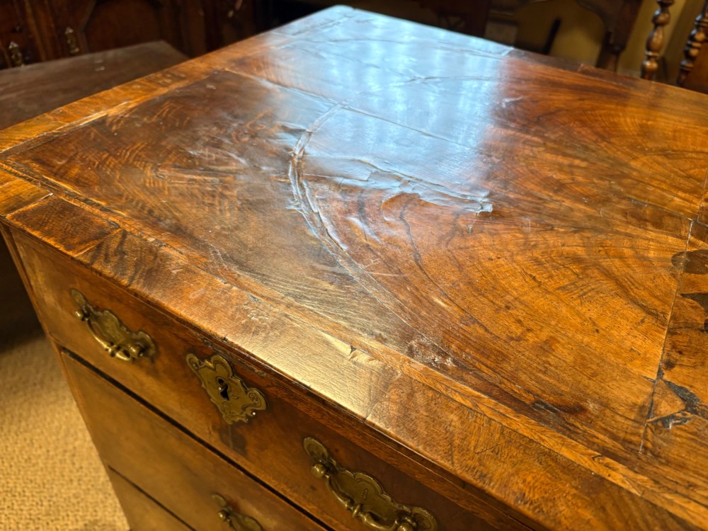 An early eighteenth-century walnut chest of drawers featuring two short drawers over two long drawers with brass drop handles and turned bun feet. View XII