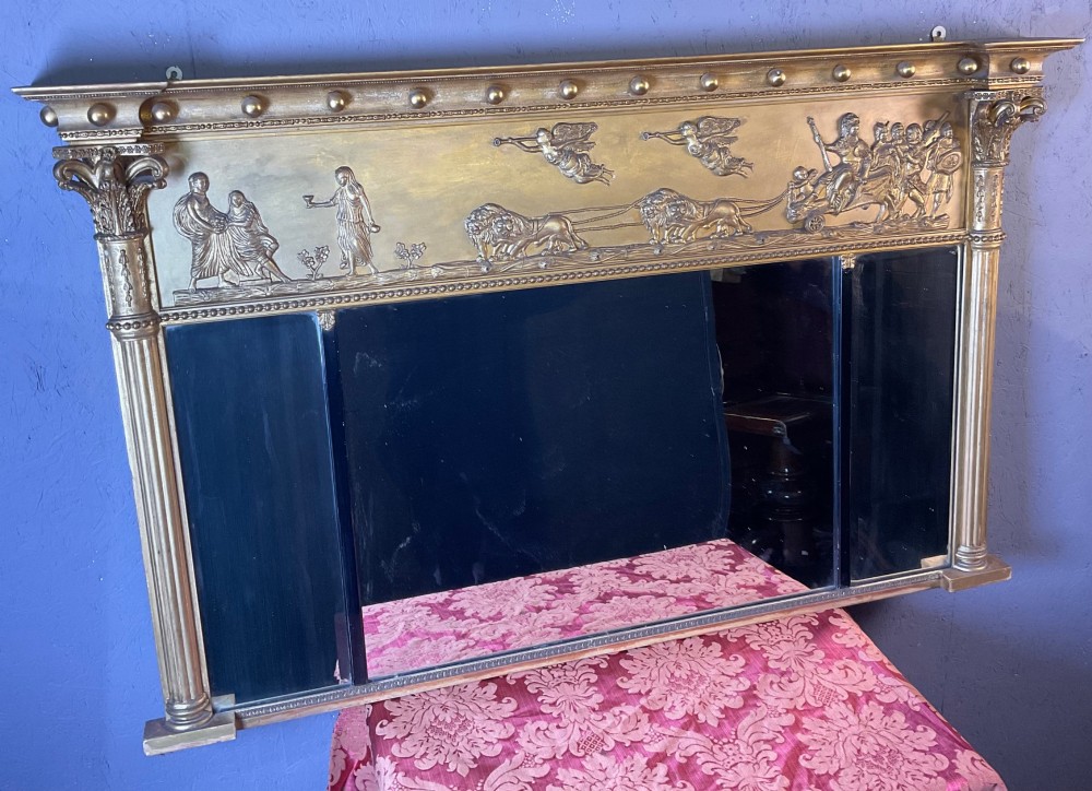 A Victorian gilded gesso overmantel mirror featuring a classical relief frieze above three mirror plates framed by fluted Corinthian columns.