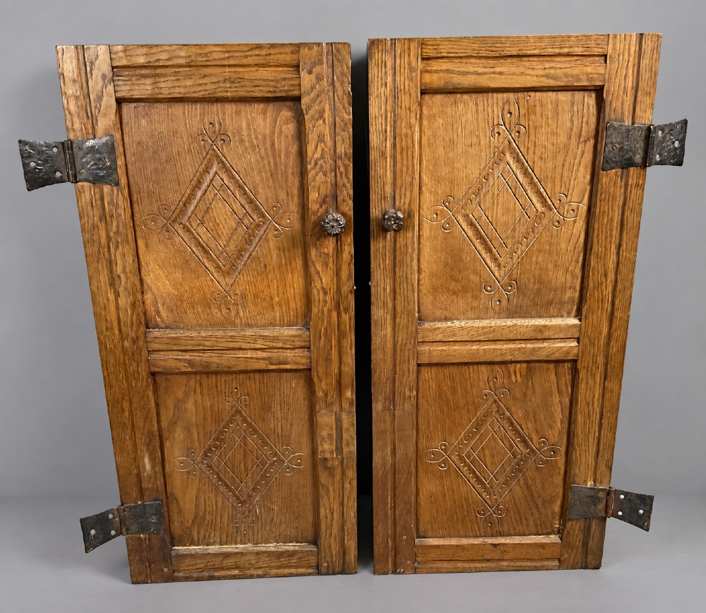 A pair of carved oak cabinet doors featuring double lozenge panel designs, floral knobs, and wrought iron strap hinges. View IV