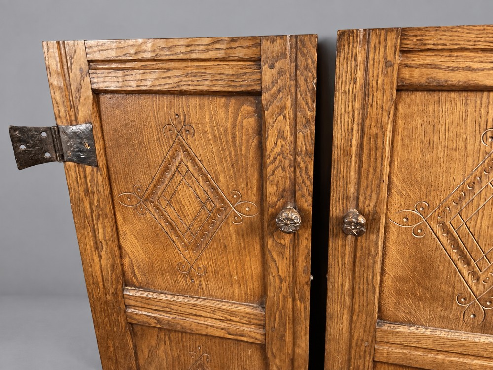 A pair of carved oak cabinet doors featuring double lozenge panel designs, floral knobs, and wrought iron strap hinges. View VII