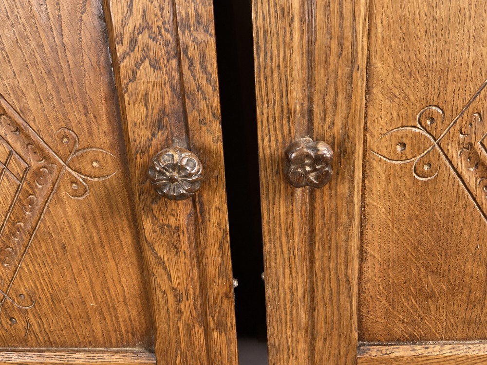 A pair of carved oak cabinet doors featuring double lozenge panel designs, floral knobs, and wrought iron strap hinges. View IX