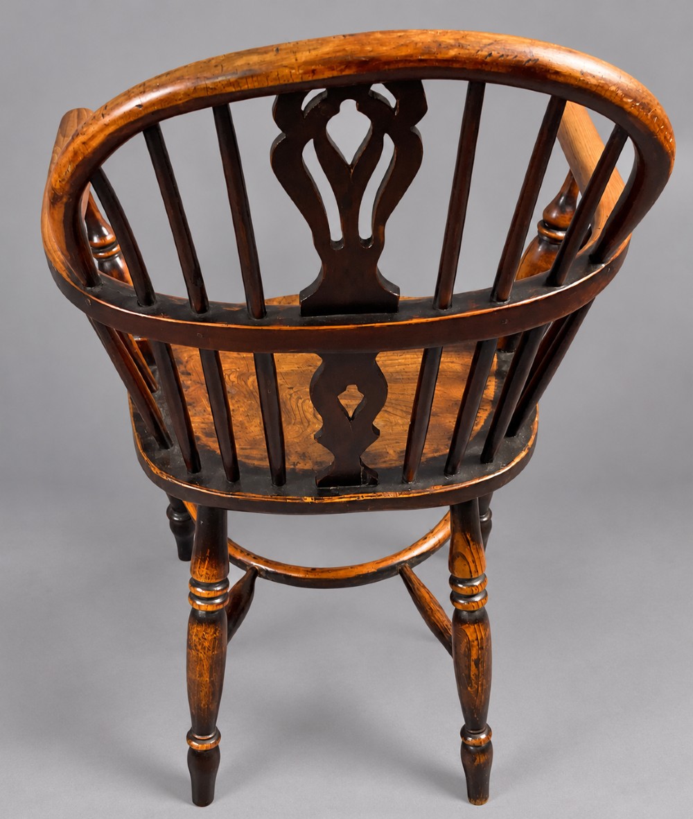 An antique yew wood low-back Windsor armchair featuring a pierced decorative back splat, turned legs, a shaped wooden seat, and a curved crinoline stretcher. View II