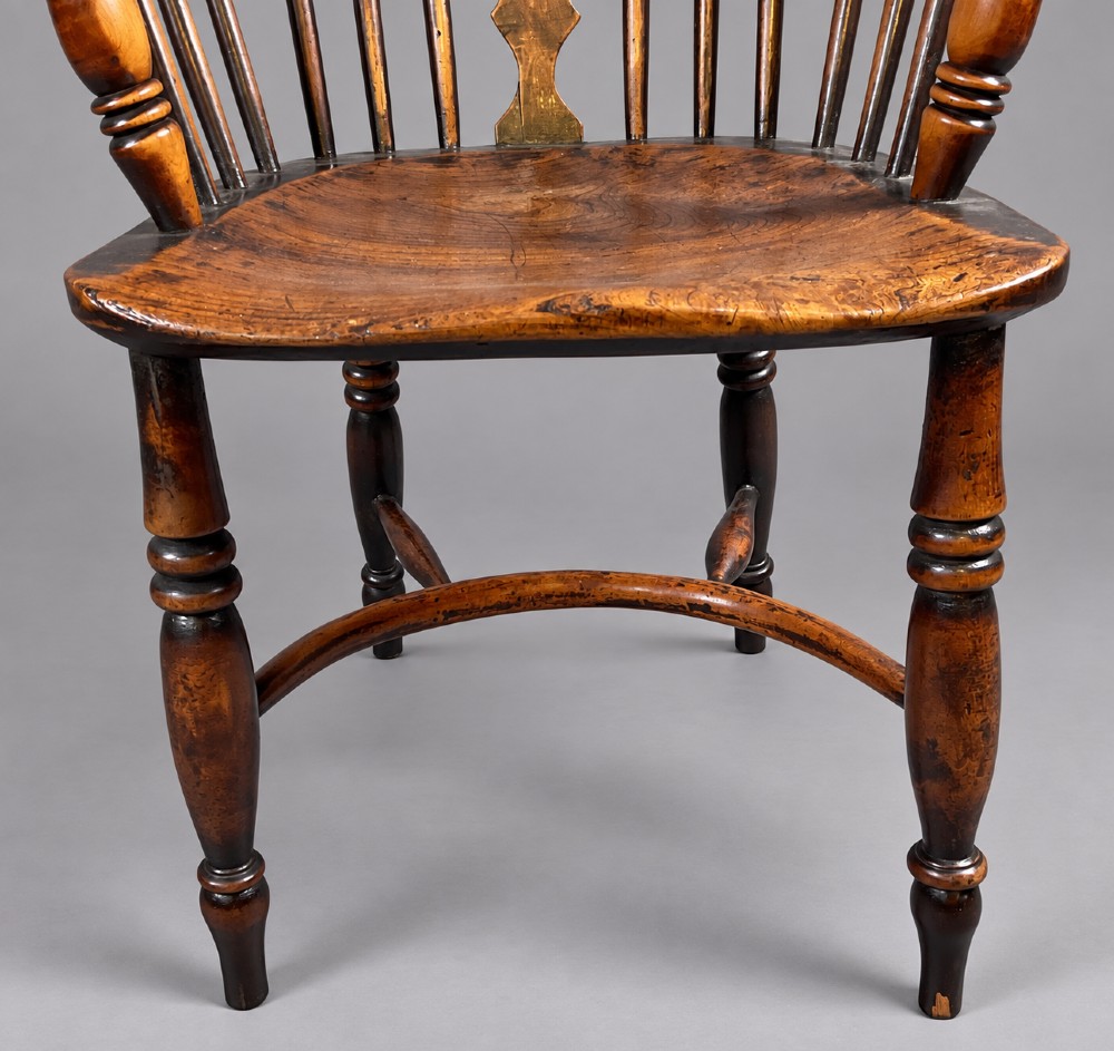 An antique yew wood low-back Windsor armchair featuring a pierced decorative back splat, turned legs, a shaped wooden seat, and a curved crinoline stretcher. View V