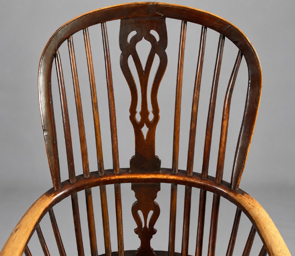 A nineteenth-century high-back yew wood Windsor armchair featuring a pierced back splat, spindled hoop back, shaped elm seat, turned legs, and a crinoline stretcher. View V