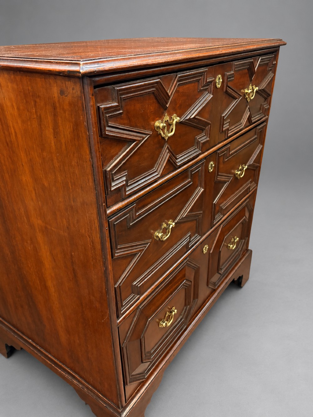 An 18th-century mahogany chest of drawers featuring geometric mitred mouldings, cast brass swan-neck handles, keyhole escutcheons, and bracket feet. View IV