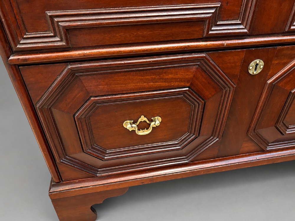 An 18th-century mahogany chest of drawers featuring geometric mitred mouldings, cast brass swan-neck handles, keyhole escutcheons, and bracket feet. View V
