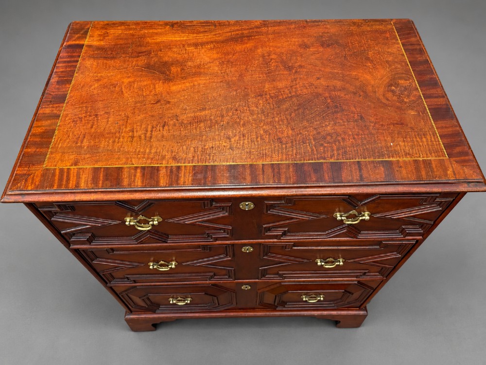 An 18th-century mahogany chest of drawers featuring geometric mitred mouldings, cast brass swan-neck handles, keyhole escutcheons, and bracket feet. View VII