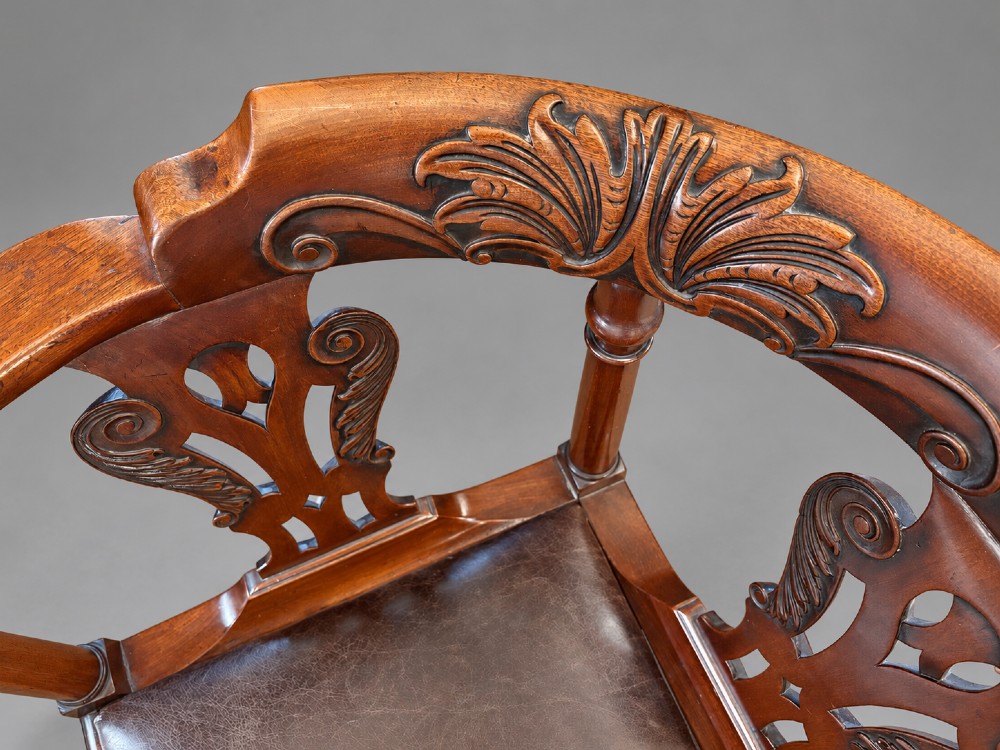An 18th century Georgian mahogany corner chair featuring carved back splats, scrolled arms, a dark leather seat, and cabriole legs with ball and claw feet. View III