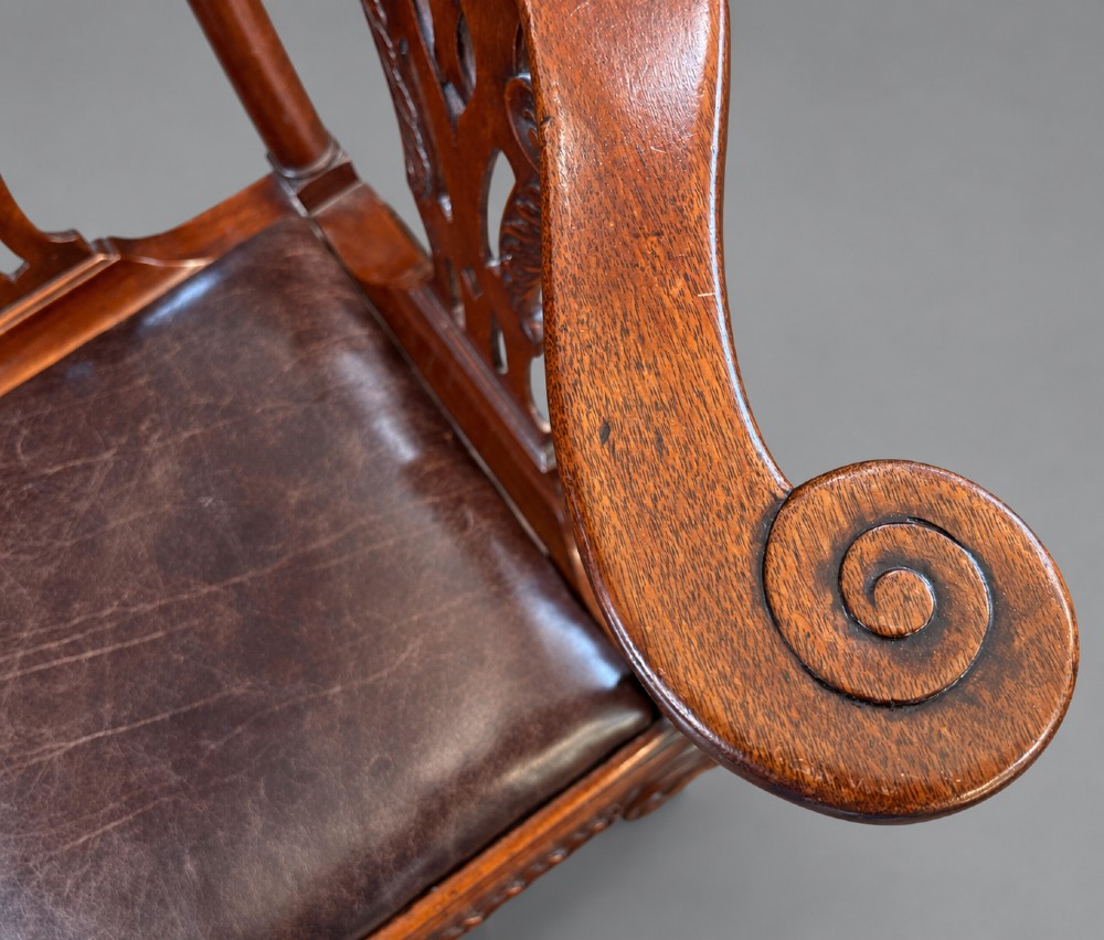 An 18th century Georgian mahogany corner chair featuring carved back splats, scrolled arms, a dark leather seat, and cabriole legs with ball and claw feet. View V