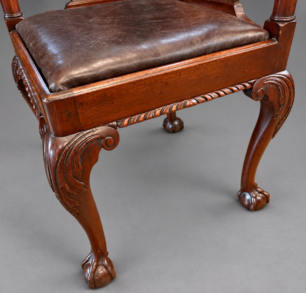 An 18th century Georgian mahogany corner chair featuring carved back splats, scrolled arms, a dark leather seat, and cabriole legs with ball and claw feet. View VI