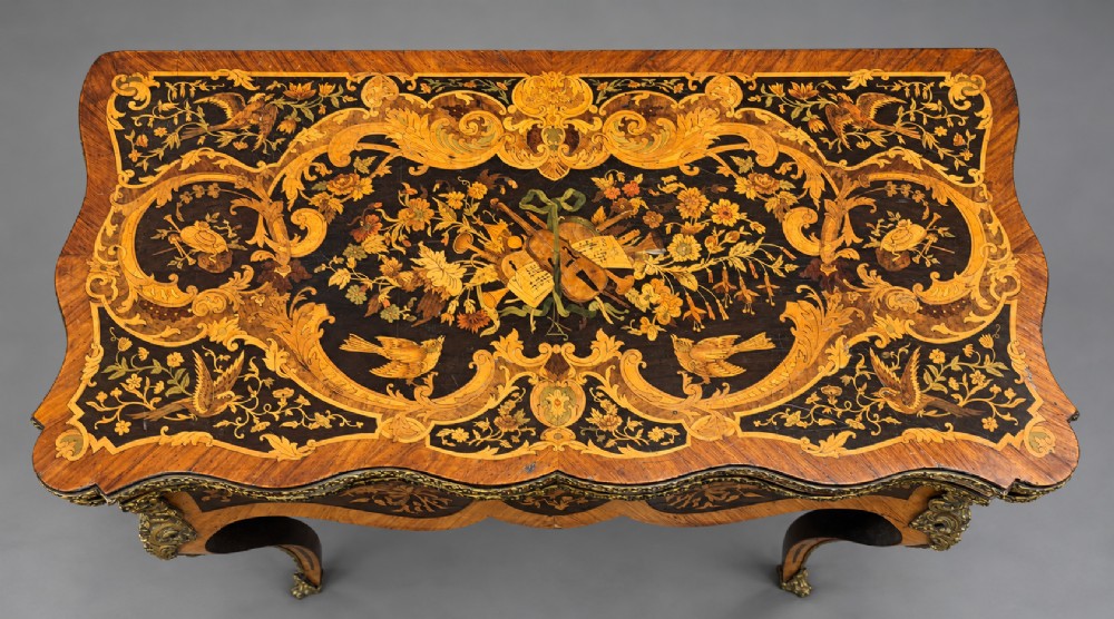 A French Rococo Revival marquetry games table featuring elaborate floral and bird inlay, cast brass mounts, and cabriole legs. View III