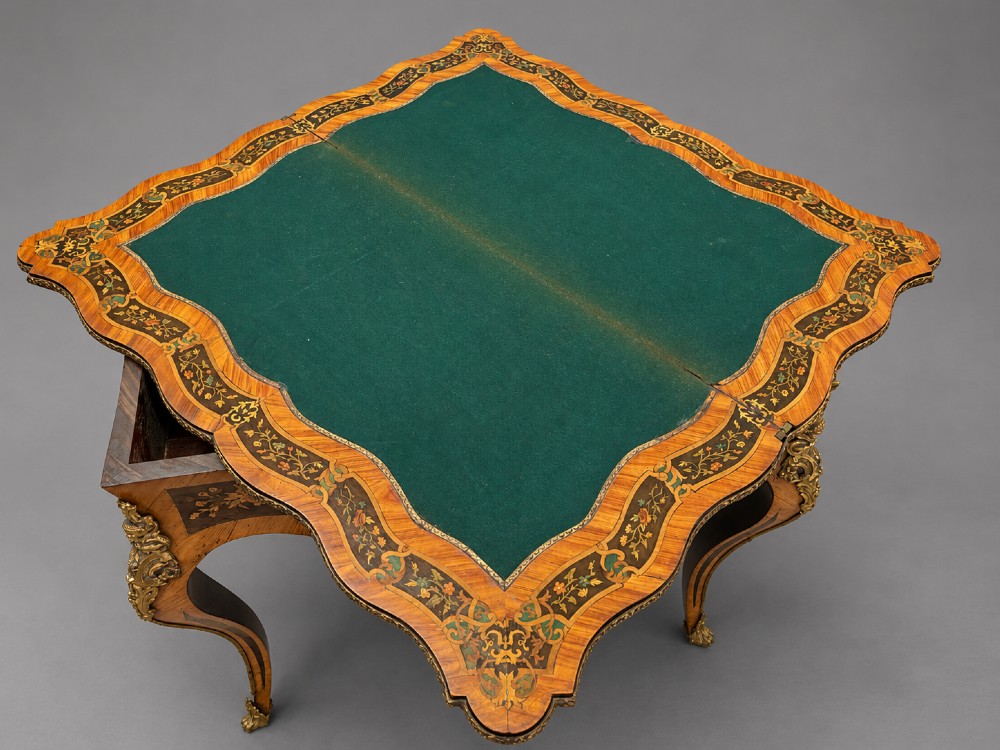 A French Rococo Revival marquetry games table featuring elaborate floral and bird inlay, cast brass mounts, and cabriole legs. View IV