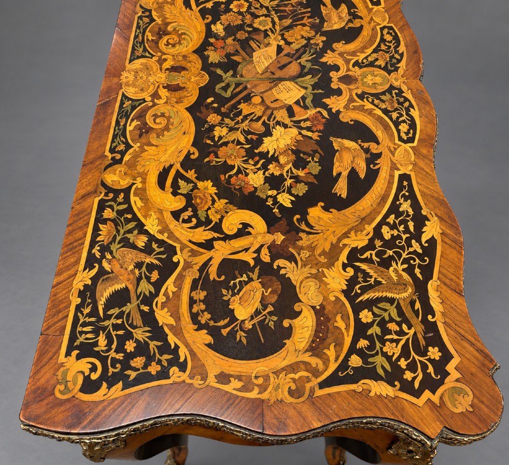 A French Rococo Revival marquetry games table featuring elaborate floral and bird inlay, cast brass mounts, and cabriole legs. View IX