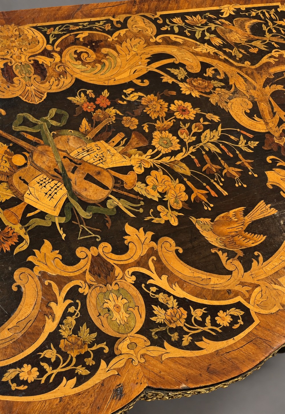 A French Rococo Revival marquetry games table featuring elaborate floral and bird inlay, cast brass mounts, and cabriole legs. View XII