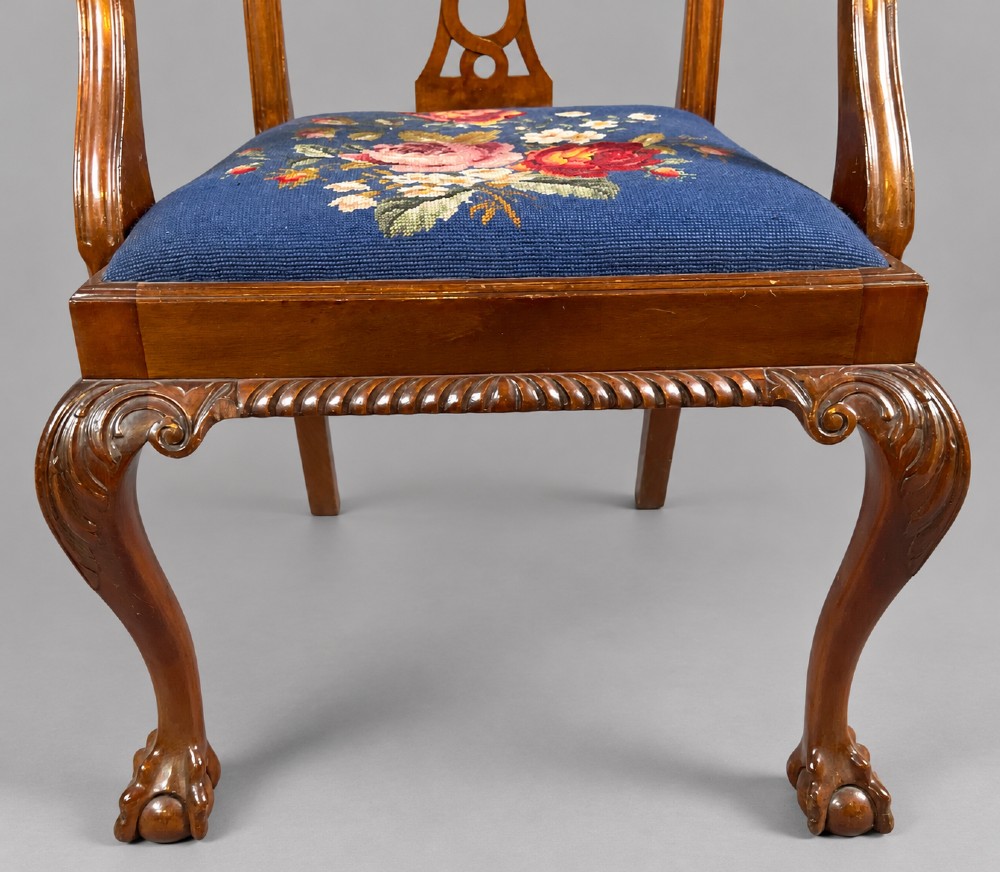 An oval mahogany extending dining table with a carved edge and winding mechanism, surrounded by eight carved wooden chairs featuring blue floral needlepoint seats. View X