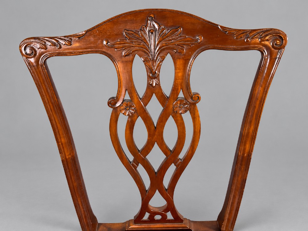 An oval mahogany extending dining table with a carved edge and winding mechanism, surrounded by eight carved wooden chairs featuring blue floral needlepoint seats. View XI