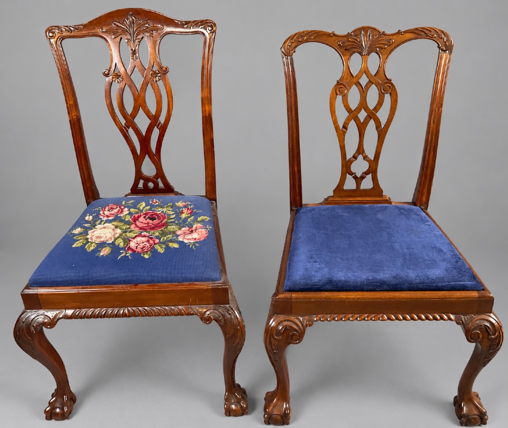 An oval mahogany extending dining table with a carved edge and winding mechanism, surrounded by eight carved wooden chairs featuring blue floral needlepoint seats. View XII