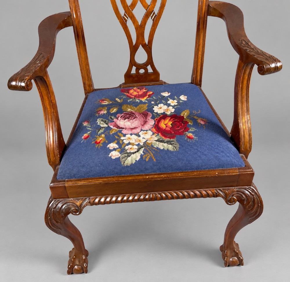 An oval mahogany extending dining table with a carved edge and winding mechanism, surrounded by eight carved wooden chairs featuring blue floral needlepoint seats. View XIV