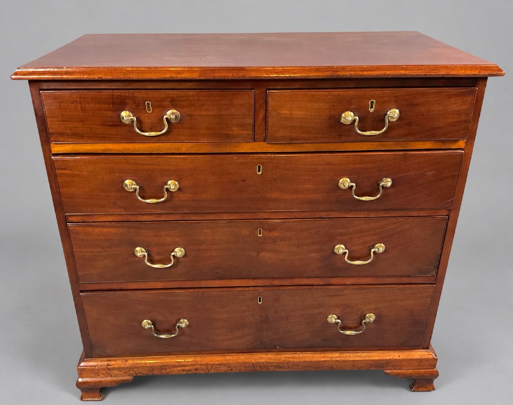 A Georgian mahogany chest of drawers featuring two short drawers over three long graduated drawers with brass swan-neck handles and bracket feet.