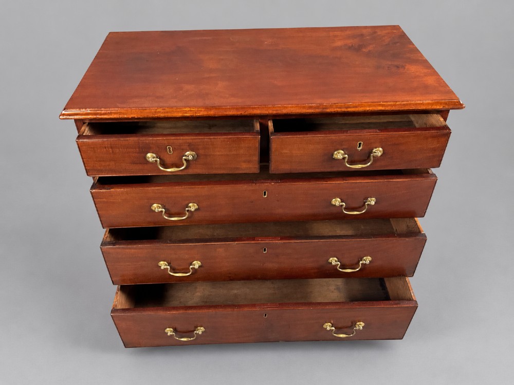 A Georgian mahogany chest of drawers featuring two short drawers over three long graduated drawers with brass swan-neck handles and bracket feet. View II