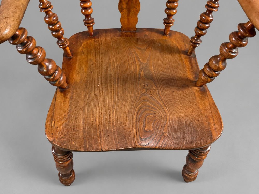 An antique Victorian wooden Windsor armchair featuring a hoop back, a central pierced splat, broad curved armrests, a shaped saddle seat, and turned legs. View IV