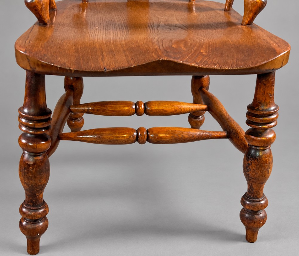 An antique Victorian wooden Windsor armchair featuring a hoop back, a central pierced splat, broad curved armrests, a shaped saddle seat, and turned legs. View VI