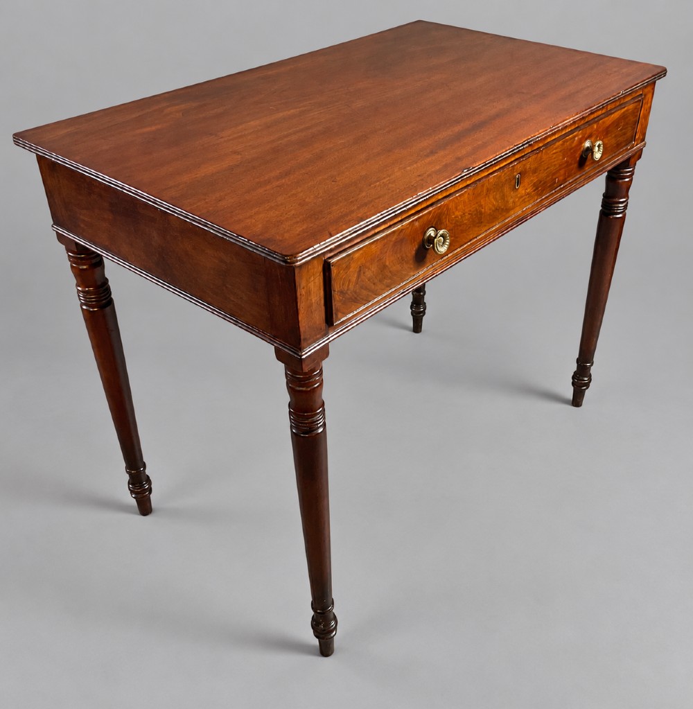 A rectangular mahogany library table featuring a single frieze drawer with brass handles and turned tapered legs.