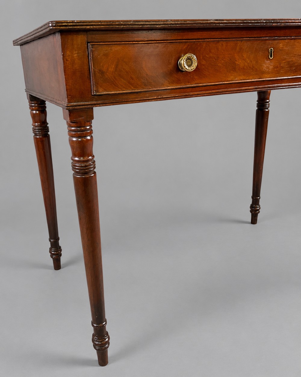 A rectangular mahogany library table featuring a single frieze drawer with brass handles and turned tapered legs. View IV