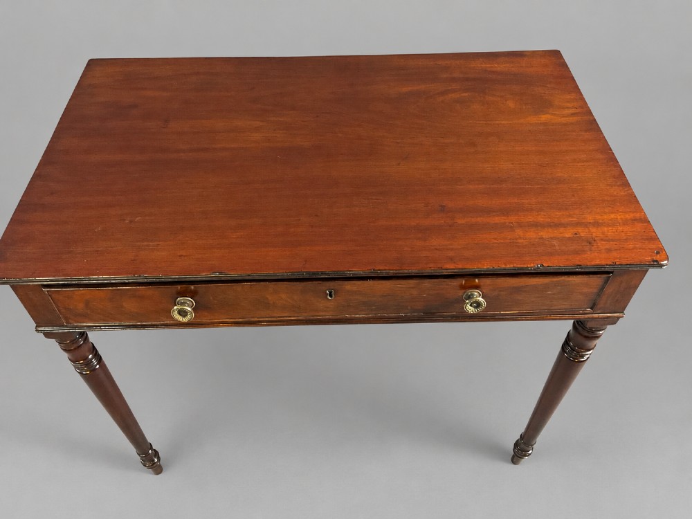 A rectangular mahogany library table featuring a single frieze drawer with brass handles and turned tapered legs. View V