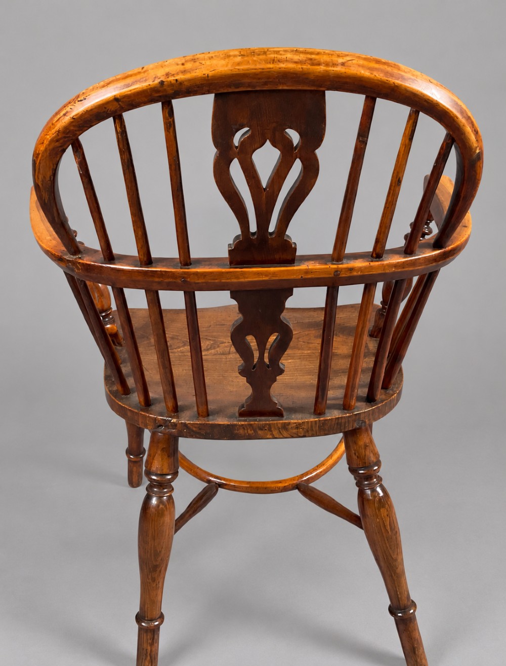 A low back antique yew wood Windsor chair featuring a contoured seat, turned legs, a crinoline stretcher, and a pierced decorative splat. View VIII