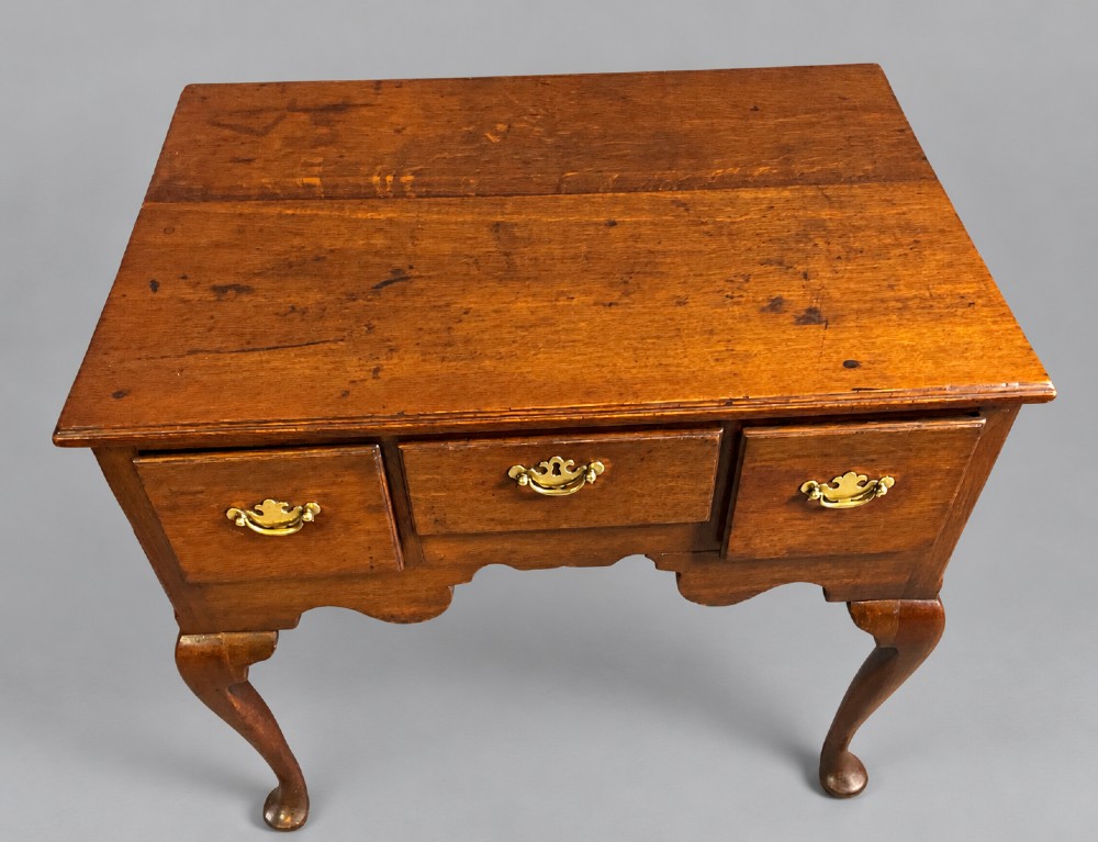A Georgian oak lowboy featuring three drawers with brass handles, a shaped apron, and cabriole legs ending in pad feet. View II