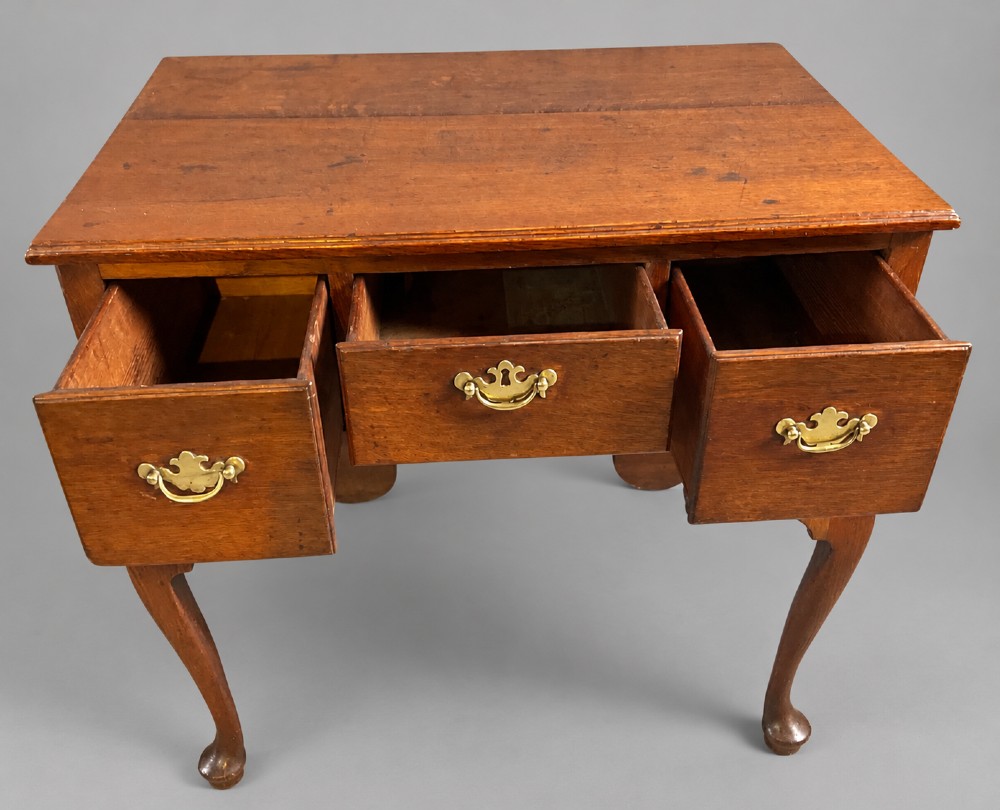 A Georgian oak lowboy featuring three drawers with brass handles, a shaped apron, and cabriole legs ending in pad feet. View III