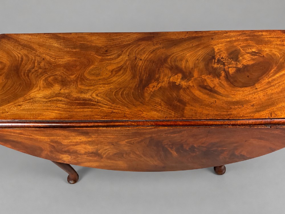 An 18th-century Georgian mahogany drop-leaf table featuring an oval top with rich grain figure and tapered legs ending in pad feet. View V