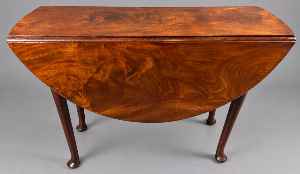 An 18th-century Georgian mahogany drop-leaf table featuring an oval top with rich grain figure and tapered legs ending in pad feet. View VI