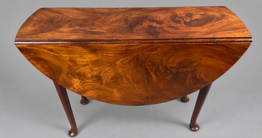 An 18th-century Georgian mahogany drop-leaf table featuring an oval top with rich grain figure and tapered legs ending in pad feet. View VII
