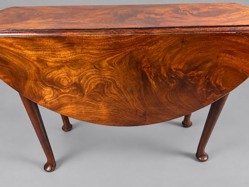 An 18th-century Georgian mahogany drop-leaf table featuring an oval top with rich grain figure and tapered legs ending in pad feet. View VIII