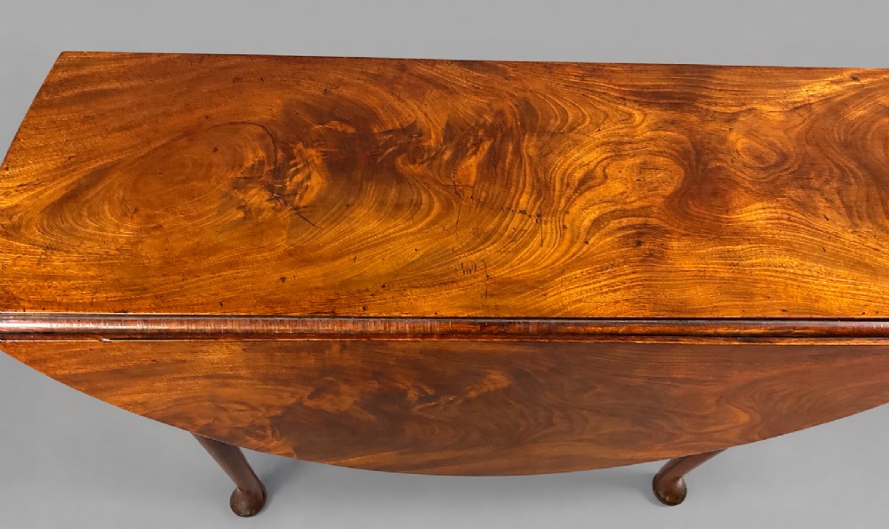 An 18th-century Georgian mahogany drop-leaf table featuring an oval top with rich grain figure and tapered legs ending in pad feet. View IX