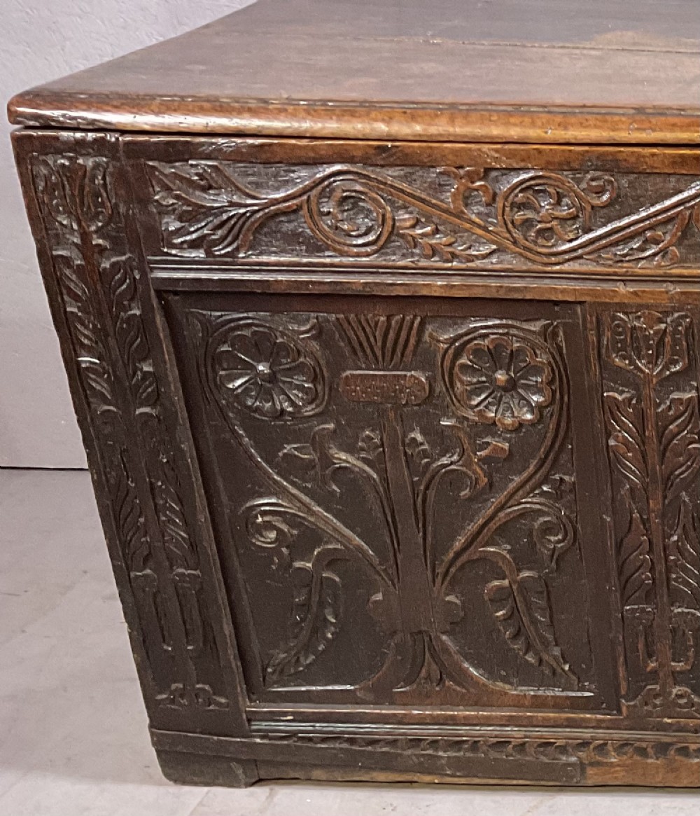 A 17th-century dark oak coffer featuring three relief-carved floral panels and a carved top frieze with a central keyhole. View IV