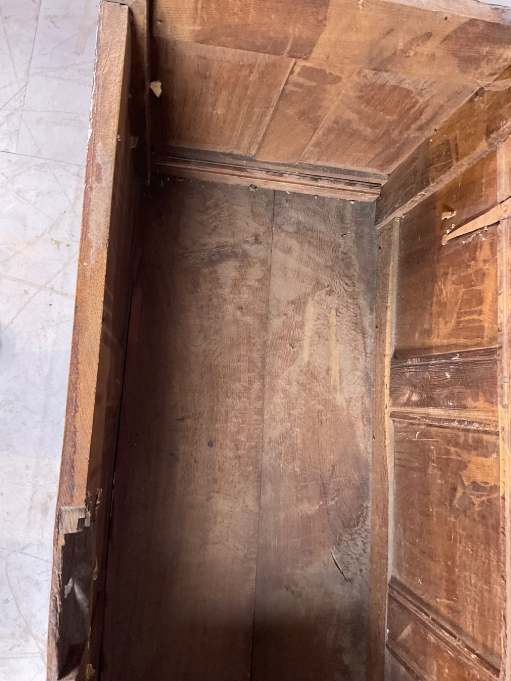 A 17th-century dark oak coffer featuring three relief-carved floral panels and a carved top frieze with a central keyhole. View VII