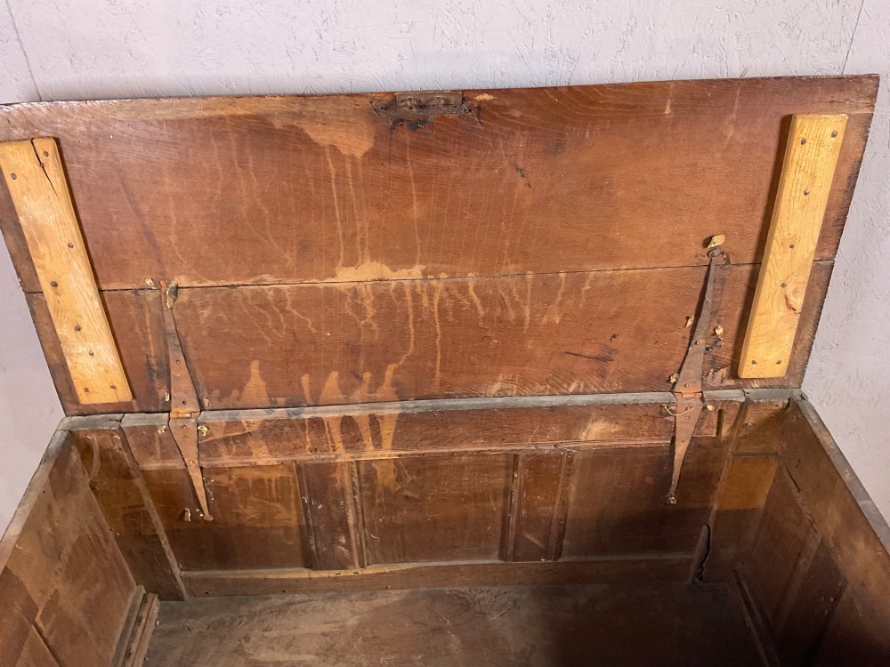 A 17th-century dark oak coffer featuring three relief-carved floral panels and a carved top frieze with a central keyhole. View XI