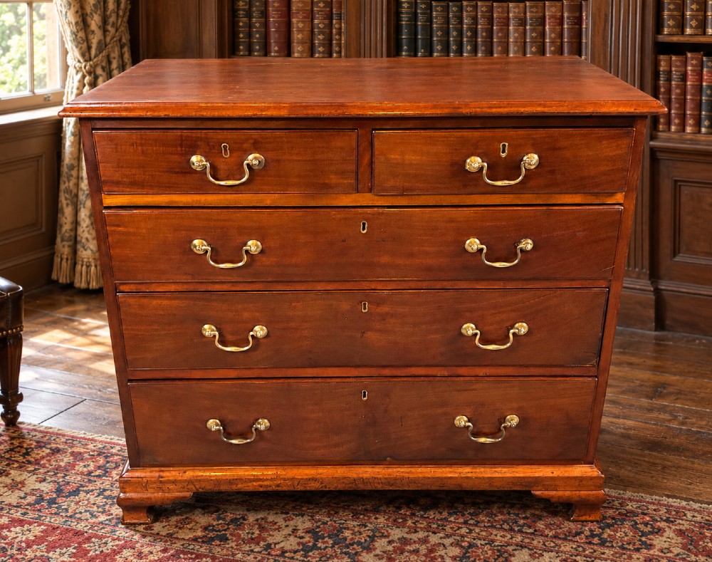 A Georgian mahogany chest of drawers featuring two short drawers over three long graduated drawers with brass swan-neck handles and bracket feet. View IX