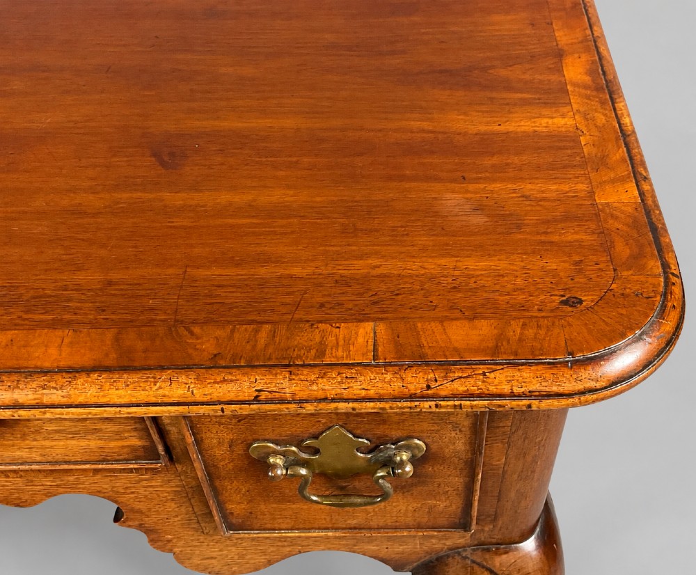 An 18th-century mahogany lowboy featuring three brass-handled drawers, a shaped apron, and four cabriole legs ending in pad feet. View V