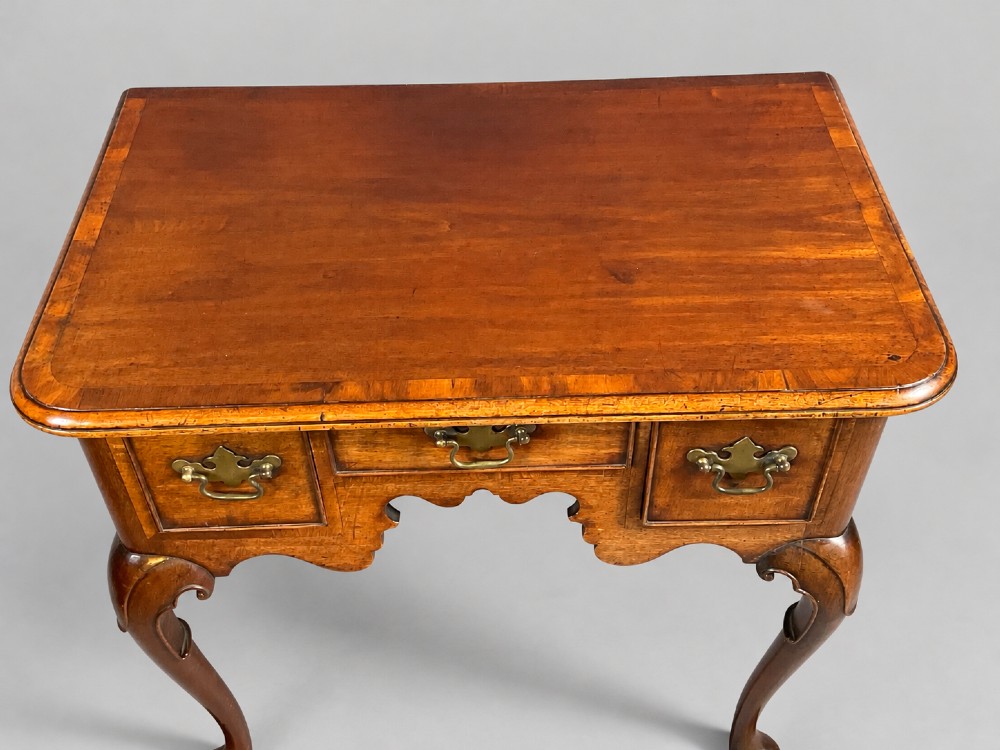 An 18th-century mahogany lowboy featuring three brass-handled drawers, a shaped apron, and four cabriole legs ending in pad feet. View IX