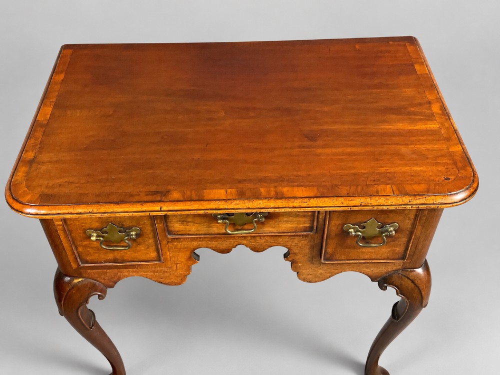 An 18th-century mahogany lowboy featuring three brass-handled drawers, a shaped apron, and four cabriole legs ending in pad feet. View XIV