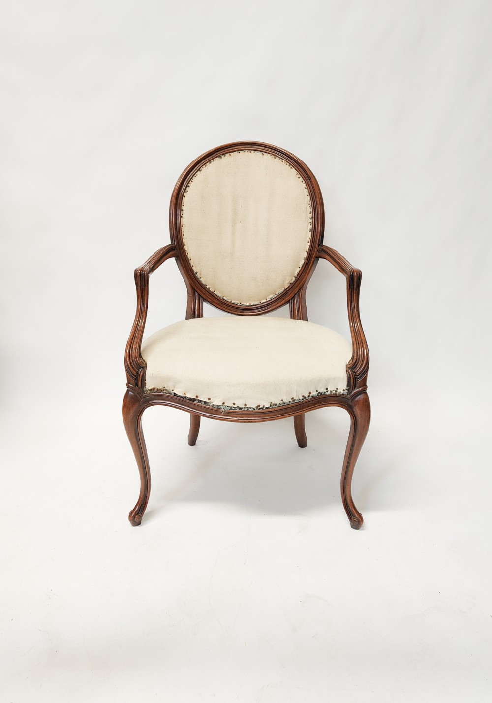 A 19th-century French open armchair featuring a carved wooden frame, medallion backrest, cabriole legs, and light cream upholstery.