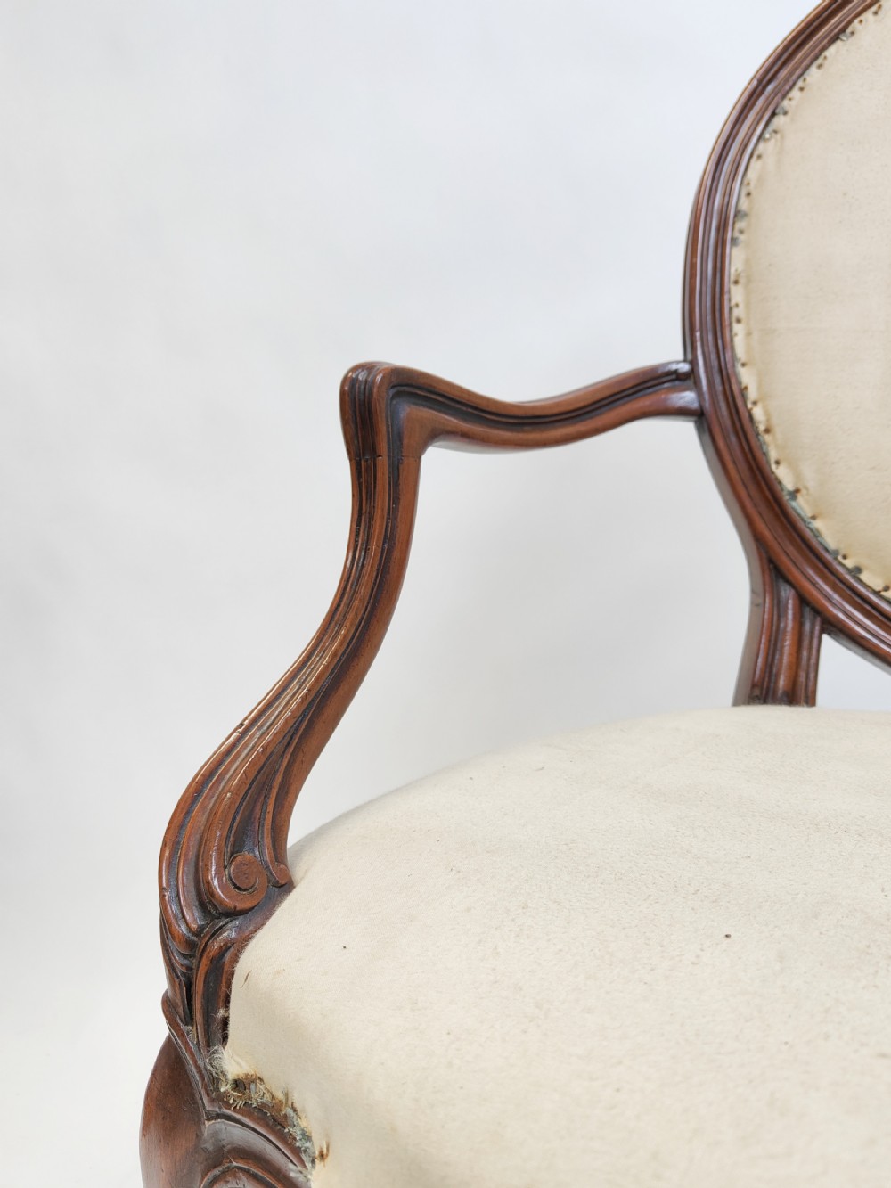 A 19th-century French open armchair featuring a carved wooden frame, medallion backrest, cabriole legs, and light cream upholstery. View V