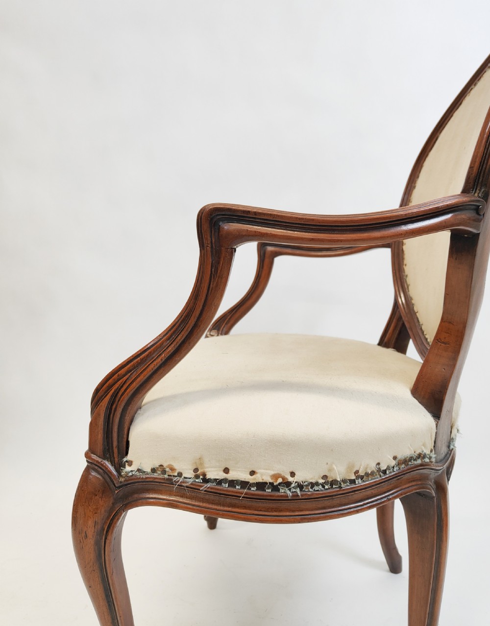 A 19th-century French open armchair featuring a carved wooden frame, medallion backrest, cabriole legs, and light cream upholstery. View VIII